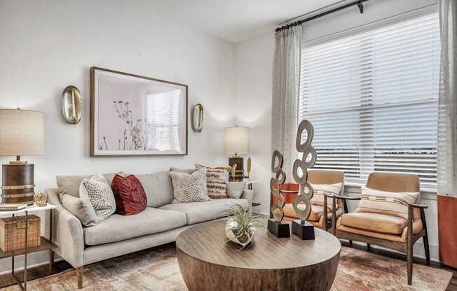 A living room with a grey couch, a wooden coffee table, and a painting on the wall.