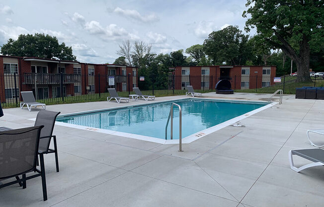 a swimming pool with chairs around it and a building in the background