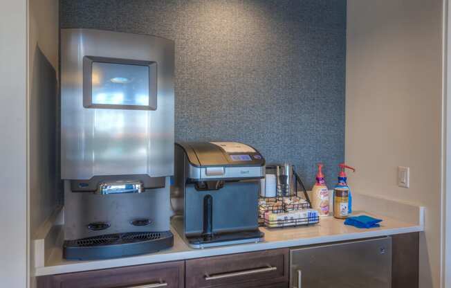 a coffee maker and espresso machine sit on a counter in clubhouse