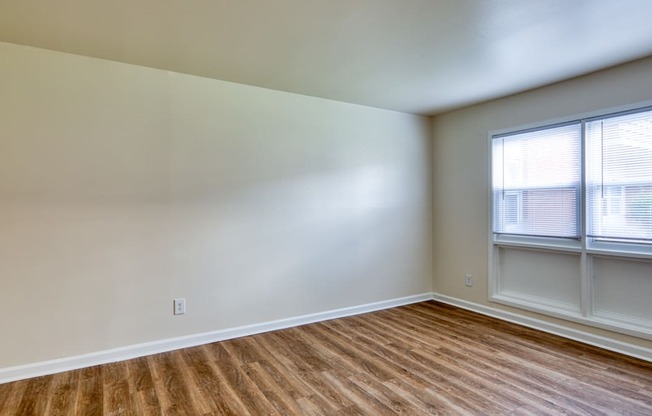 an empty room with wood flooring and two windows at Gates of West Bay in VA 23503