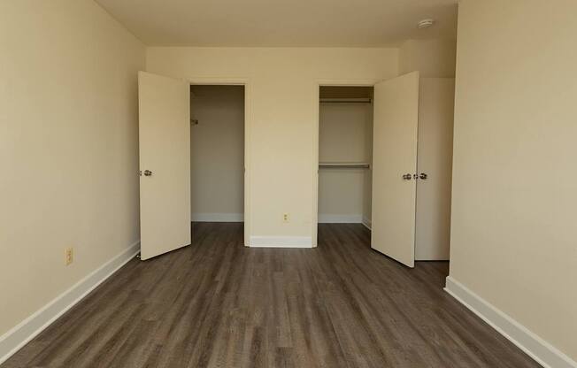 A room with wood flooring and three doors.