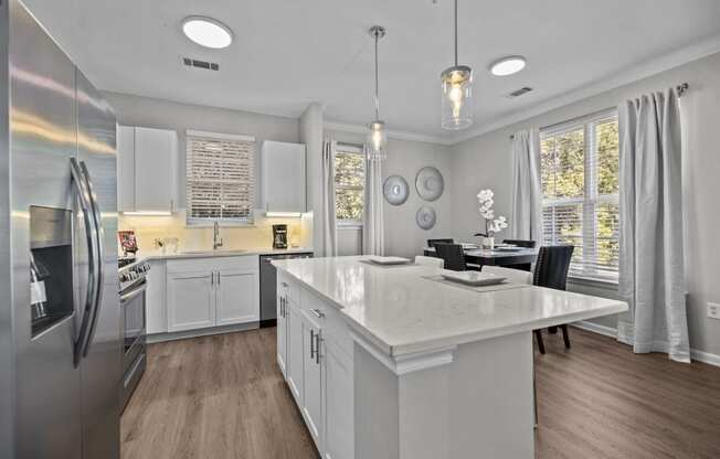 a white kitchen with a large island and stainless steel appliances