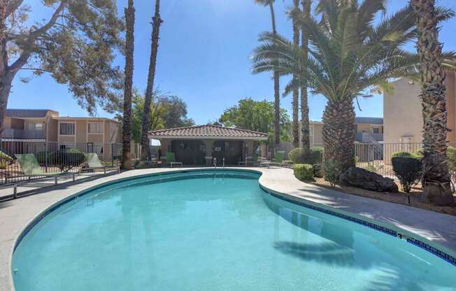 A swimming pool surrounded by palm trees and a building in the background.