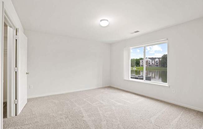 A room with a carpeted floor and a window showing a view of a house and trees.