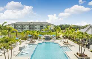 a large swimming pool with palm trees and a building in the background