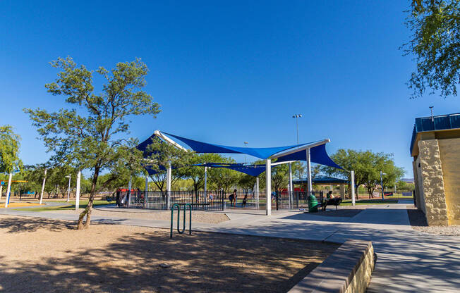 a park with a blue and white canopy over a playground