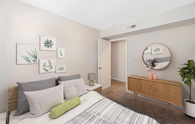 A bedroom with a bed, nightstand, and a round mirror on the wall.