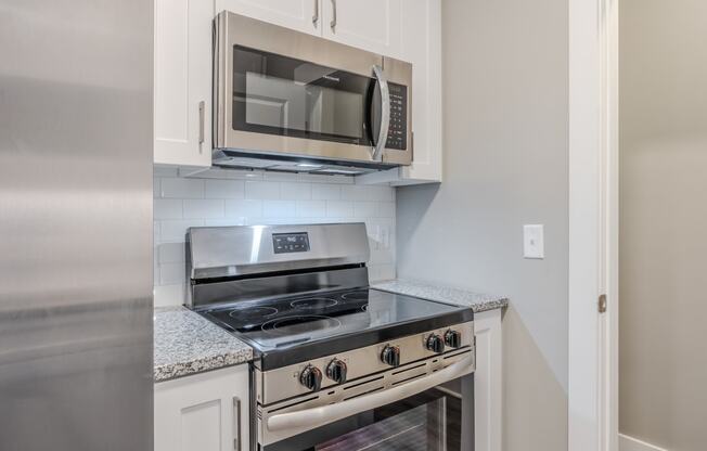 a kitchen with white cabinets and a stove and microwave