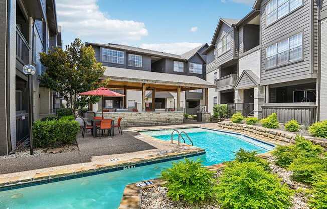 A swimming pool surrounded by a patio with chairs and a table.