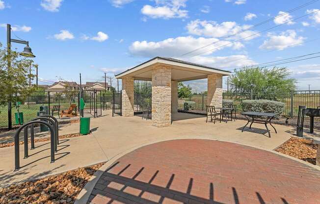 A park with a gazebo, benches, and a brick walkway.