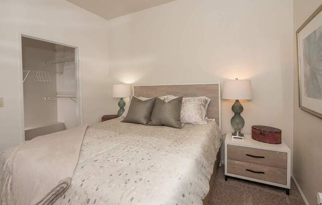 A bedroom with a bed, nightstand, and two lamps at Autumn Oaks Apartments, Roseville, CA, 95678