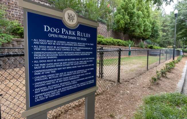 a sign for dog park rules in front of a fence