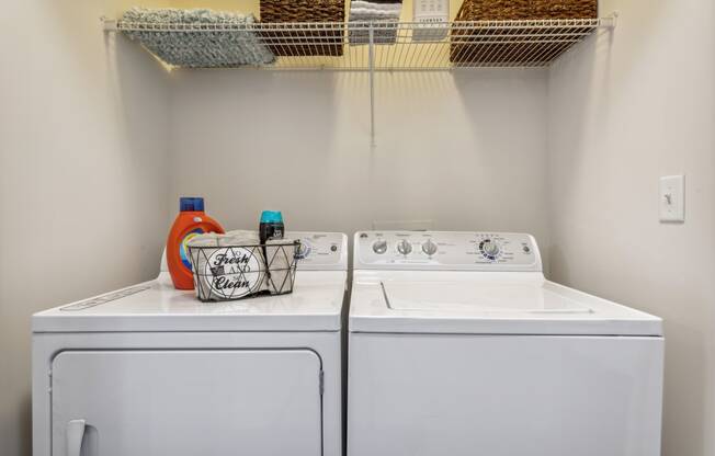 a washer and dryer in a laundry room with a shelf over the top