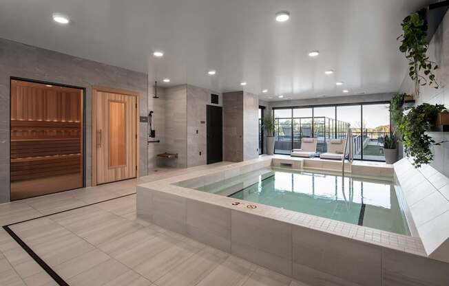 A modern indoor swimming pool with a wooden door and a glass wall.