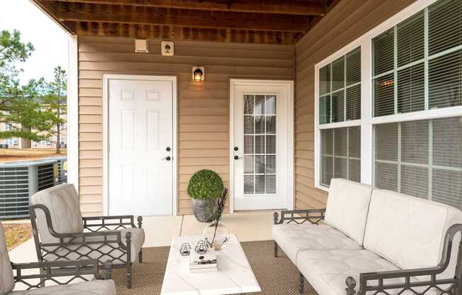 A small patio with a white couch, chair, and coffee table.