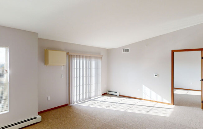 an empty living room with a sliding glass door and