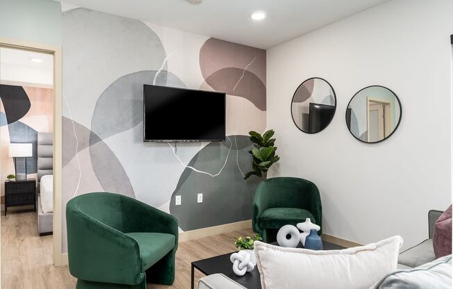 a living room with two green chairs and a television on the wall