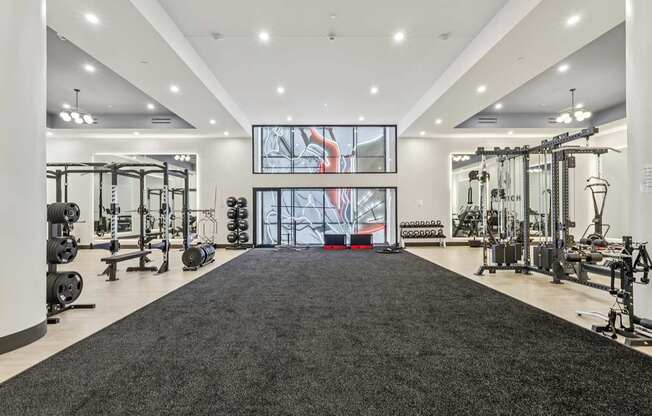 A spacious gym with a variety of equipment and a large mirror on the wall.