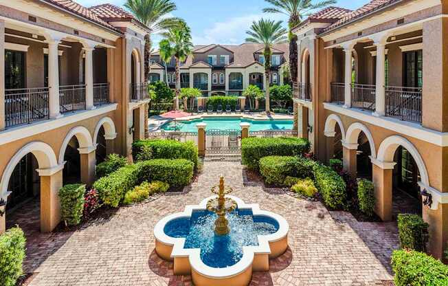 Tranquil courtyard fountain framed by palm trees and Mediterranean-style architecture.