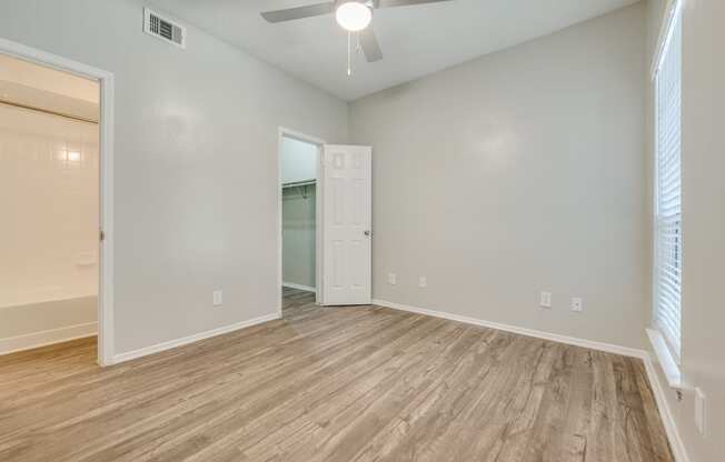 an empty living room with wood flooring and a ceiling fan