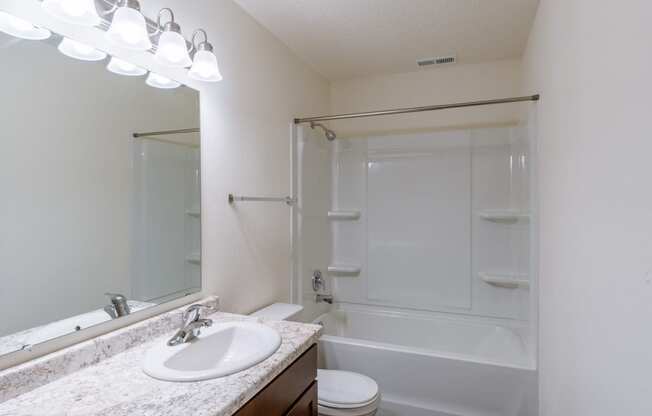 a bathroom with a sink and a toilet and a shower. Fargo, ND Westwood Apartments