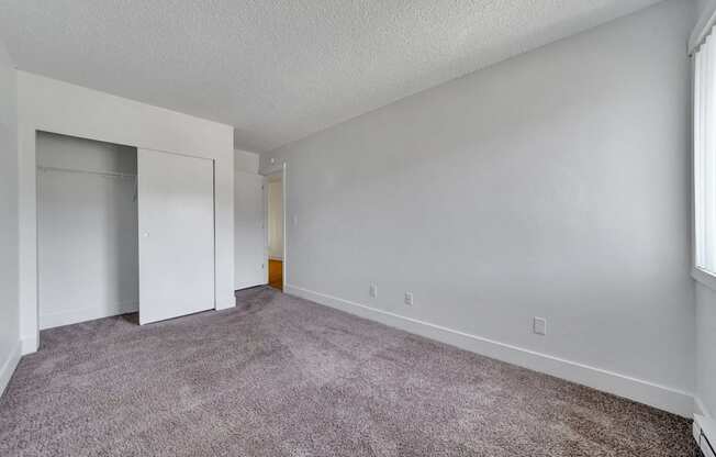 a bedroom with a carpeted floor and a closet with a mirrored door