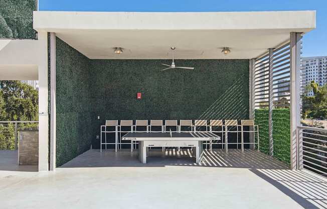 1- & 2-Bedroom Apartments for Rent in Miami, FL – Riverview One Apartments – A patio with a ping pong table and chairs under a white roof.