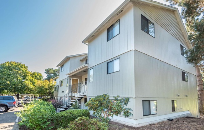 A modern two-story building with a white exterior and a balcony on the second floor.