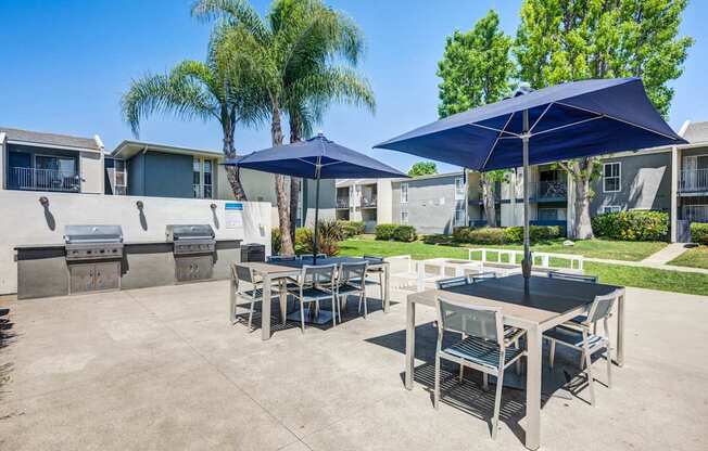 A patio with a table and chairs under umbrellas.