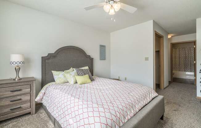Master bedroom with ceiling fan and attached bathroom at Northridge Heights in Lincoln