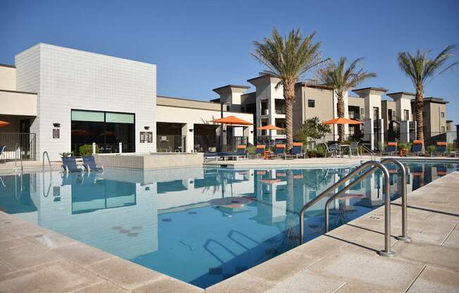 A swimming pool in front of a building with palm trees.