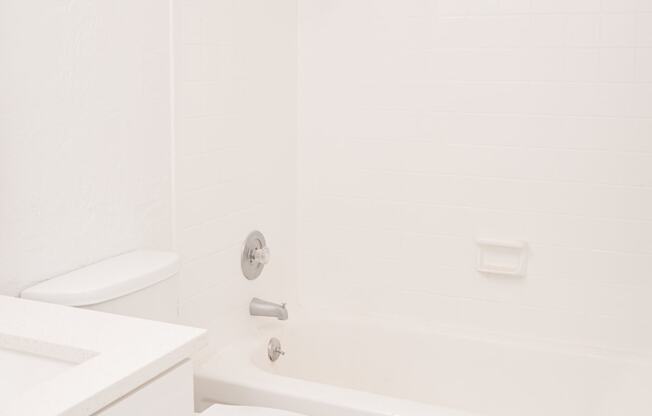 a bathroom with white fixtures and a white bathtub