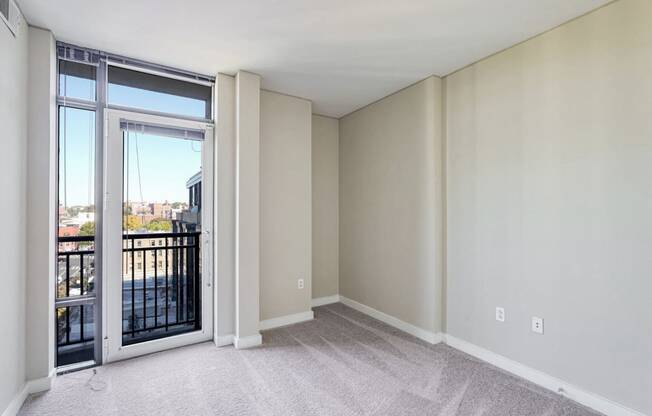 an empty living room with a balcony and a door to a balcony