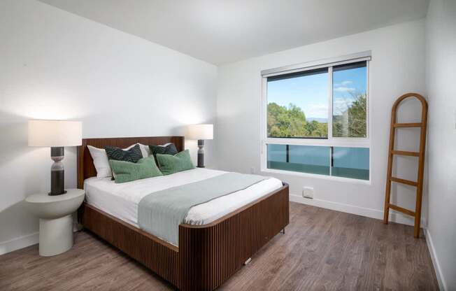 A bedroom with a large bed, a window with a view, and a wooden floor.