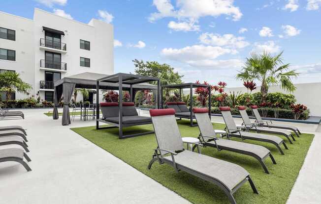 a row of lounge chairs and umbrellas in front of a building