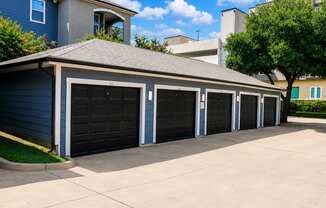 A row of black garage doors in front of a blue house.
