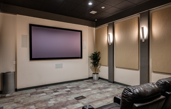 a movie theater with leather chairs and a screen on the wall