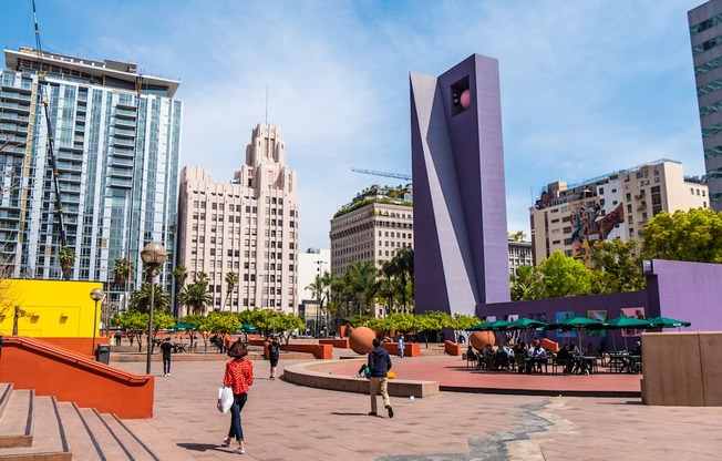 A woman in a red shirt is standing in front of a large purple sculpture.