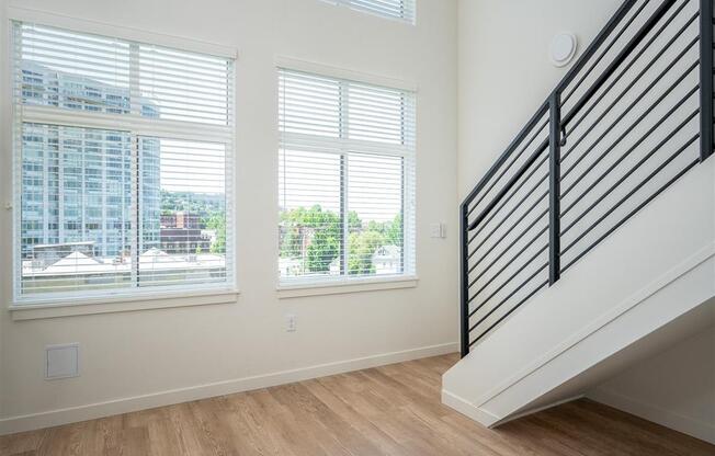 a living room with three windows and a staircase