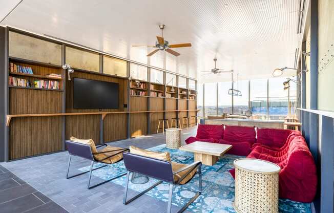 a living room with a red couch and chairs and a tv