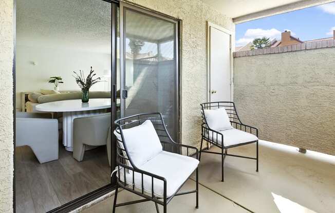 a small balcony with two chairs and a table