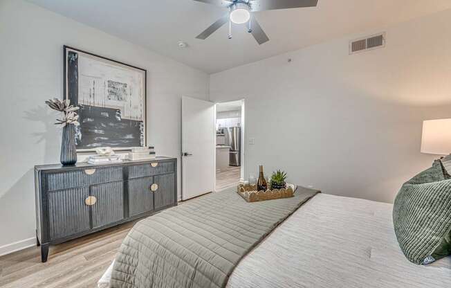 A bedroom with a large bed and a dresser with a vase on top.