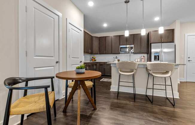 A modern kitchen with a wooden table and bar stools.