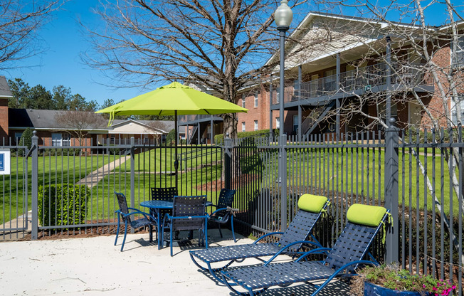 A patio with a table and chairs and a green umbrella.