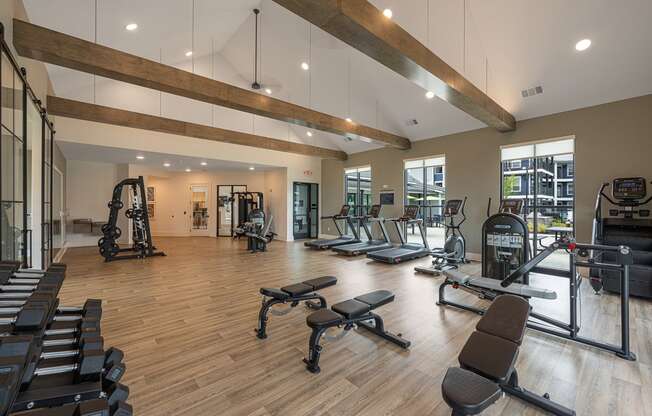 a gym with cardio equipment and weights on a wood floor