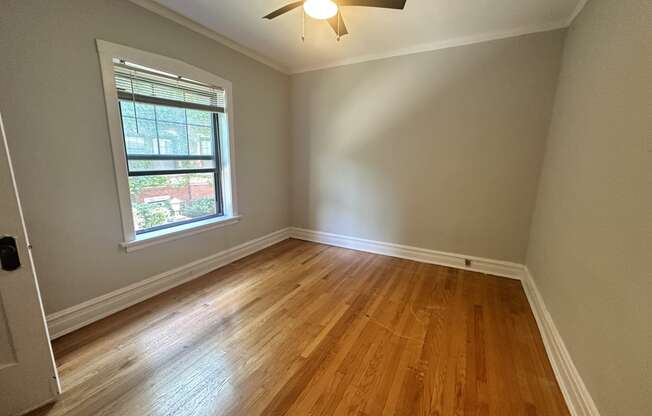 an empty bedroom with hardwood floors and a ceiling fan