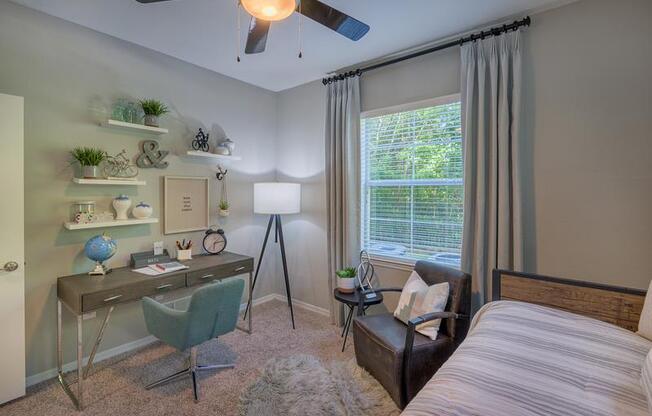 Guest bedroom and office with a window, ceiling fan, large windows, high ceiling, and carpeted flooring at Evergreens at Mahan apartments in Tallahassee, FL