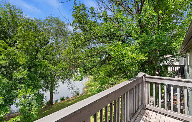 A balcony with a view of a lake and trees.