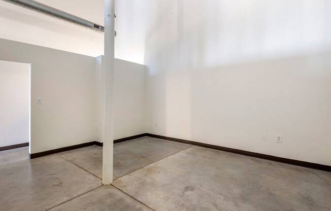 an empty room with white walls and a concrete floor and a pole at Highland Mill Lofts, North Carolina