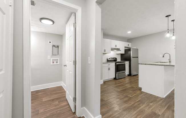 a renovated kitchen and living room with white walls and wood flooring